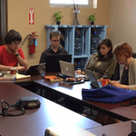 Students Elliot Schwartz '19, James Smith '19, and Jordan Kobbervig '19 at the Dakotah Language Institute. Three students and one professor sit working at a table.