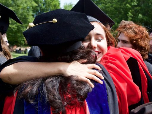 Students in graduation outfits hugging each other