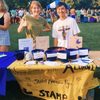 two students stand behind a table