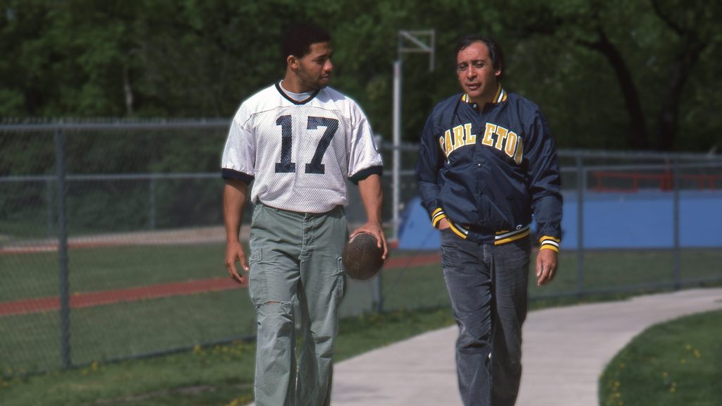 Coach and athlete walk along a sidewalk