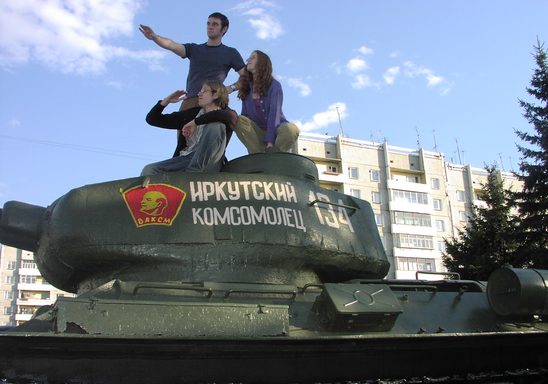Three Students on the 2005 Carleton Moscow Program climb on top of an old Soviet tank in Siberia.