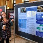 a student shows her academic poster to a professor