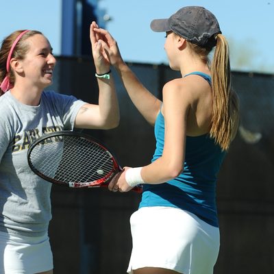 Two students high-five on a tennis court
