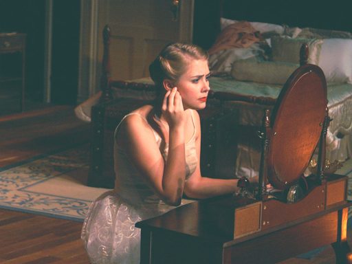 A woman sitting at a mirror and putting in earrings