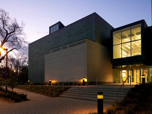 The main entrance of the Weitz Center, at night, with lights in the windows.